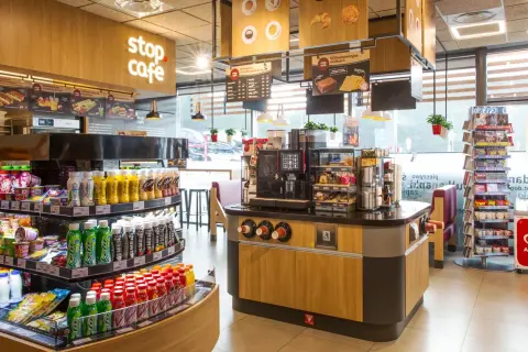 Wnętrze kawiarni Stop Cafe z ladą, ekspresem do kawy, półkami z napojami i przekąskami.