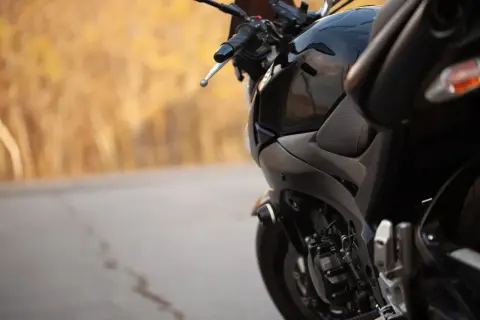 Czarny motocykl na tle jesiennego krajobrazu. Zastanawiasz się, jaki przebieg dla motocykla jest duży? Ten wygląda na gotowy na wiele przygód.
