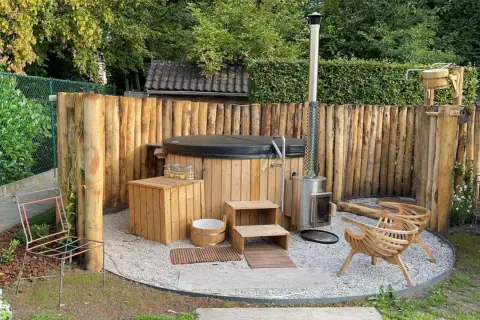 Gemütliche whirlpool ecke im garten gestalten: Holzzaun, Hot Tub, Holzofen, Sitzgelegenheiten und Holzbottich schaffen eine entspannende Oase.