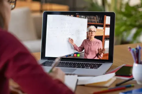 Nauczycielka tłumaczy matematykę na lekcji zdalnej na ekranie laptopa.