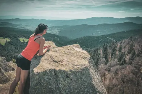 Une randonneuse admire le paysage depuis un rocher. Une parfaite destination randonnée pour s'évader.