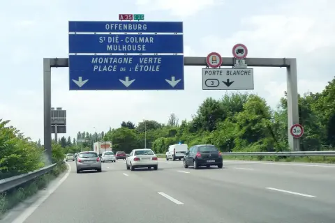Sur l'autoroute A35, des panneaux indiquent Offenburg, Mulhouse et la Porte Blanche. Des voitures circulent par une journée nuageuse.
