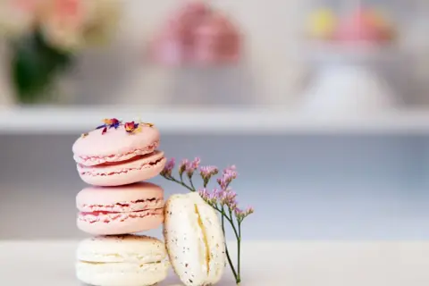 En stapel rosa och vita macarons, dekorerade med blommor. Perfekt för ett macarons recept.