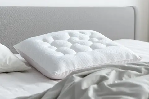 A white pillow with a textured surface rests on a bed, showing how a pillow should support you with its unique design for ultimate comfort.