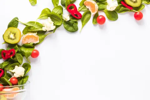 Kolorowe warzywa i owoce, takie jak kiwi, pomarańcza, papryka i pomidorki, tworzą kompozycję idealną dla diety wegańskiej.