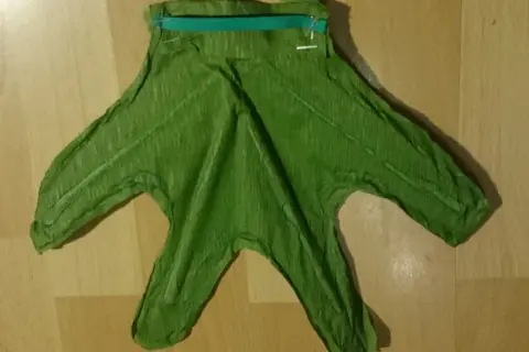 Zielone strój żabki dla dziecka, z zielonym zamkiem na górze, gotowy do zabawy.
