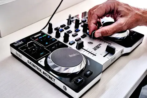 Dłoń DJ-a manipuluje pokrętłem na konsoli DJ Hercules DJControl Instinct.