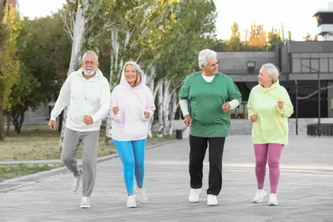 Quatre seniors souriants font du jogging en plein air, une belle illustration des activités pour préparer sa retraite.