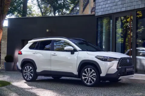 Biała Toyota Corolla Cross zaparkowana przed nowoczesnym budynkiem. Poznaj jej wymiary i możliwości.