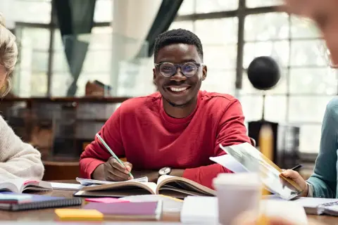 Jóvenes sonrientes estudiando juntos, una experiencia que inspira a estudiar en el extranjero.