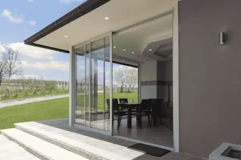 Techar un patio sin perder luz es posible con este diseño de cristal. El interior, con mesa y sillas, se integra al jardín.