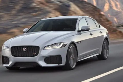 Srebrny Jaguar XF pędzi po pustynnej drodze. Czy jaguar xf jest drogi w utrzymaniu? To pytanie zadaje sobie wielu miłośników tej marki.