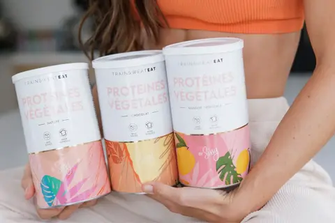 Trois boîtes de protéines végétales "Trainsweat Eat" aux saveurs Nature, Chocolat et Mangue Tropicale. Idéal pour savoir combien de protéine par jour consommer.