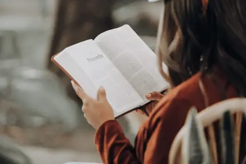 Une influenceuse littéraire lit le livre des Proverbes, absorbant la sagesse ancienne.