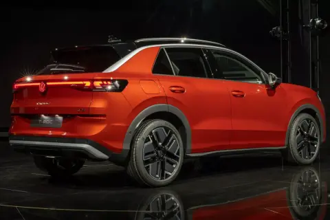 Pomarańczowy Volkswagen T-Roc z czarnym dachem, stylowymi felgami i nowoczesnymi światłami. Sprawdź aktualną volkswagen t-roc cena.