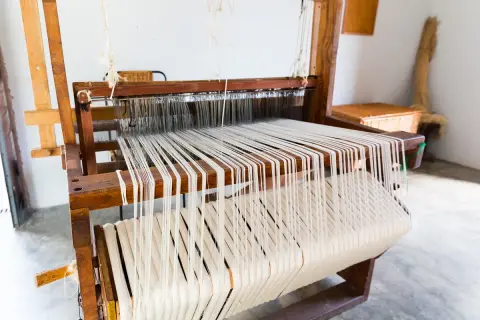 Telai in legno con fili bianchi pronti per creare tessuti come quelli del Medioevo.