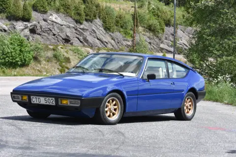 Blå Matra Bagheera sportbil parkerad vid en bergssluttning med grönska.