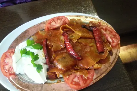 Iskender kebab z sosem pomidorowym, jogurtem, papryczkami i pomidorami.