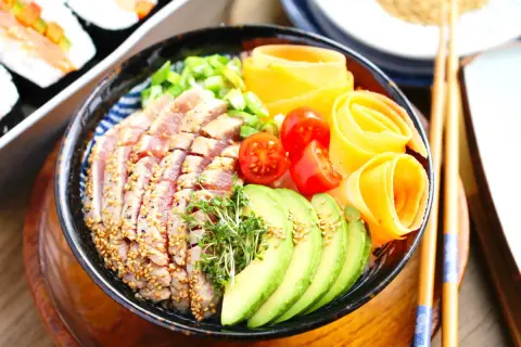 Ein bunter Chirashi Bowl mit Thunfisch, Avocado, Tomaten und Karottenröllchen.