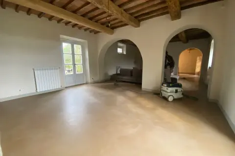 Interno con soffitto a travi, pareti in tinteggiatura a calce e un aspiratore professionale pronto per la pulizia.