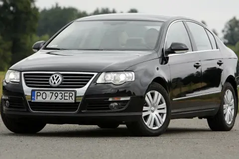 Czarny Passat B6 z polskimi tablicami PO 793ER na tle zieleni.