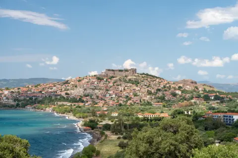 Widok na malowniczą wioskę z zamkiem na wzgórzu, turkusowe morze i zielone wzgórza. Lesbos atrakcje zachwycają!