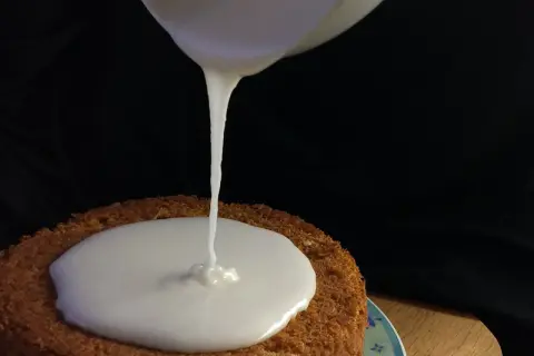 Ein cremiger zuckerguss mit milch fließt auf einen Kuchen.