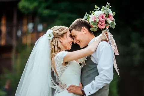 Un couple s'embrasse tendrement, le bouquet de la mariée rappelant une fête foraine. Un mariage plein de joie et d'amour.