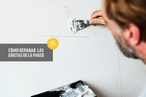 Hombre aplicando masilla para reparar grietas en la pared. Guía visual sobre cómo reparar grietas en la pared.