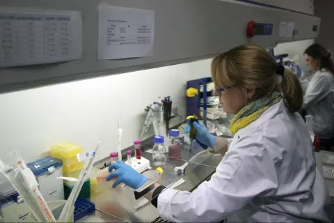 Naukowczyni w laboratorium pracuje z pipetą i próbówkami.