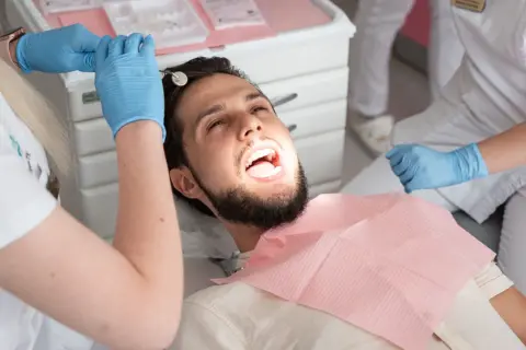 Pacjent u dentysty, który bada zęby. Może to być próchnica pod plombą, która wymaga uwagi.