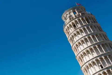 La Torre di Pisa dritta, un'illusione ottica sotto un cielo azzurro.