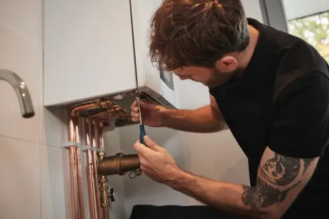 Un technicien ajuste une chaudière. Attention, trop de pression chaudière dangereux.