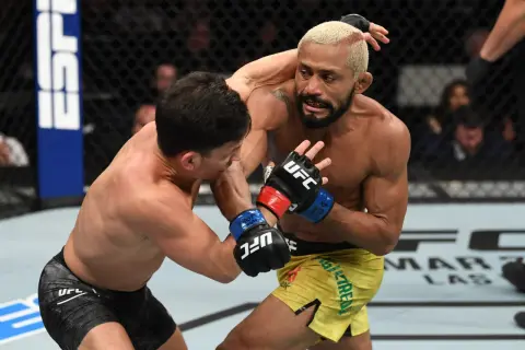 Two fighters in a flyweight weight bout exchange punches in the octagon.