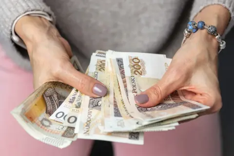 Dłonie trzymające plik banknotów 200 zł. To może być wypłata, oszczędności, a może nawet słynne "kosiniakowe".