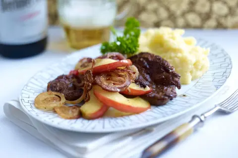 Herzhaft gebratene leber mit zwiebeln und apfel, dazu Kartoffelpüree und ein Bier.
