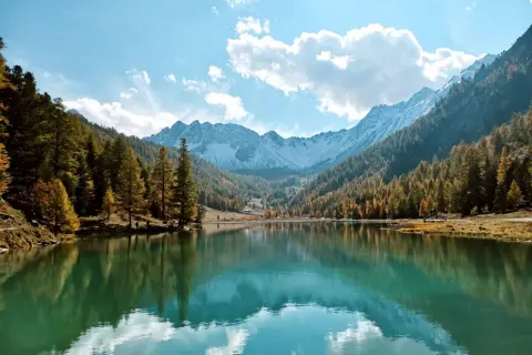 Le lac de l'Orceyrette, miroir des montagnes enneigées et des forêts d'automne, sous un ciel bleu éclatant.