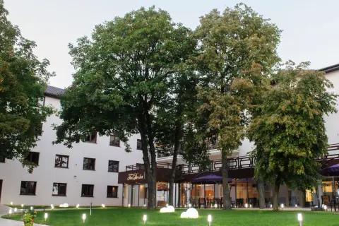 Nowoczesny budynek Teodorka Med & Spa otoczony zielenią i oświetlony lampkami.