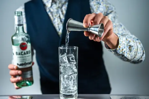 Barman nalewa Bacardi do szklanki z lodem, przygotowując klasycznego Cuba Libre.