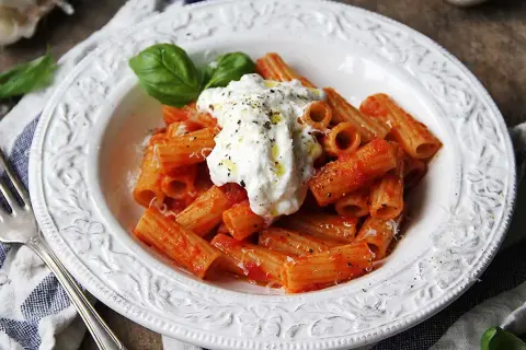 En krämig burrata pasta med rigatoni i tomatsås, toppad med färsk basilika och svartpeppar.