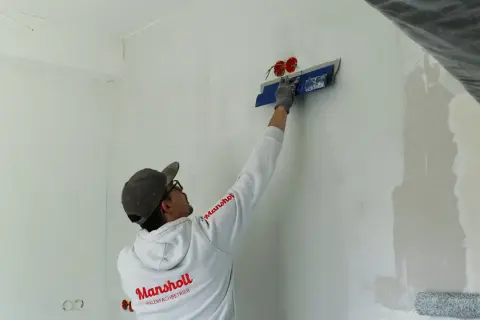 Maler spachtelt Rigips-Wand glatt für ein makelloses Finish.