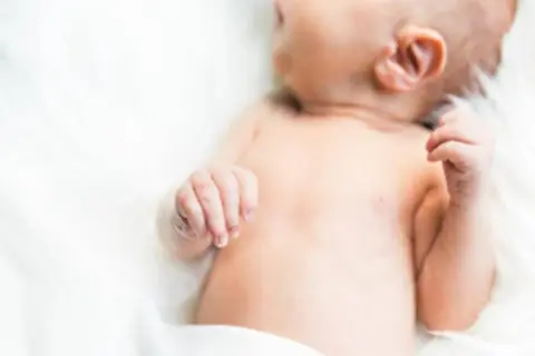 Delikatna skóra niemowlęcia, być może zmagającego się z trądzikiem niemowlęcym lub skazą białkową, otulona bielą.