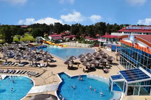 Słoneczny aquapark nad morzem z basenami, zjeżdżalniami i leżakami pod parasolami.