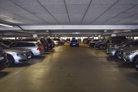 Un garaje lleno de coches, con un coche azul en el centro. Los gastos de compra de garaje son altos.