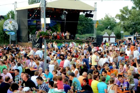 Menschen feiern beim Weinfest Sand am Main. Eine Band spielt auf der Bühne, während Gäste an Tischen sitzen und die Atmosphäre genießen.