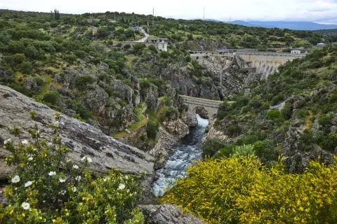 Paisaje natural con un río caudaloso, un puente de piedra y una presa. Un lugar ideal que ver en Robledillo de la Jara para disfrutar de la naturaleza.