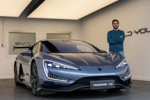 Hombre posa junto al deportivo BYD Yangwang U9, con diseño futurista y luces LED llamativas.