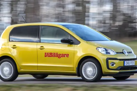 Gul Volkswagen Up körs på en väg, med texten "ViBilägare" på sidan. En potentiell vw up problem kan vara att den är för liten för familjen.