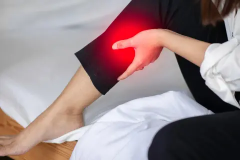 A person holds their leg, which is highlighted in red, indicating pain. This image explores the question: can a bad mattress cause leg pain?