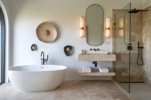 Salle de bain moderne avec baignoire îlot, lavabo en pierre et douche à l'italienne. Le sol et les murs de la douche sont en travertin 1er ou 2ème choix, apportant une touche naturelle et élégante.